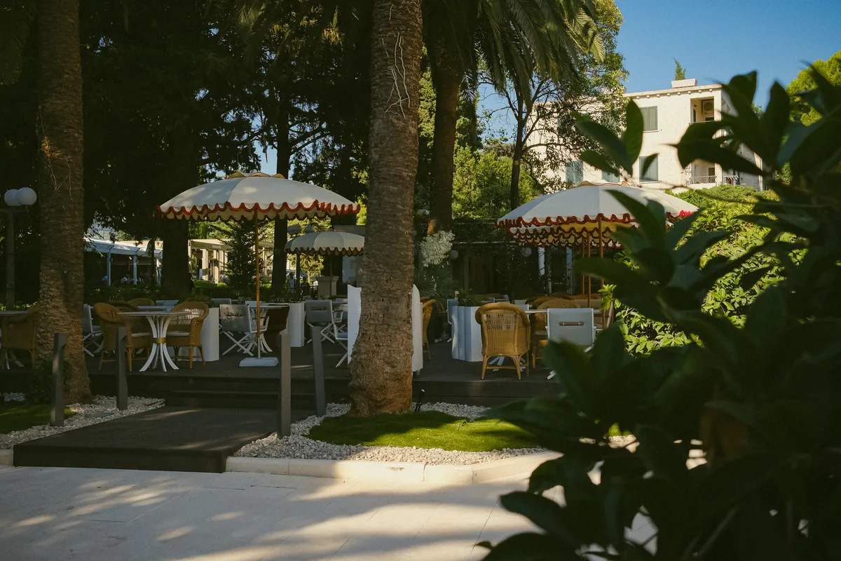 Garden terrace tables under parasols, framed by palms